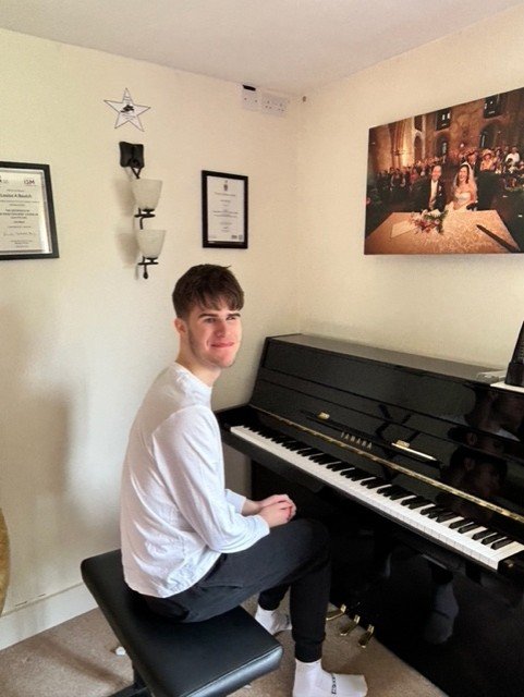 Felix next to a piano, smiling at the camera